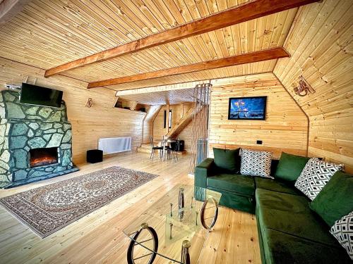 a living room with a green couch and a fireplace at Hillside Kazbegi in Stepantsminda