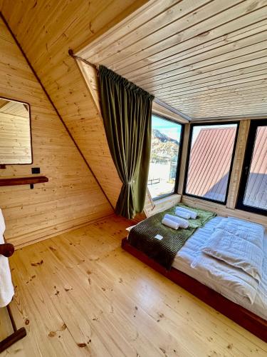 a bedroom with a bed in a room with windows at Hillside Kazbegi in Stepantsminda