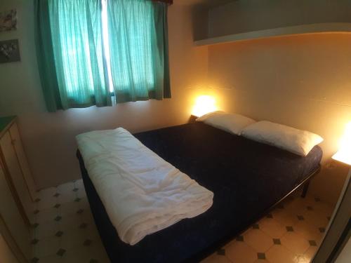a bedroom with a bed with white sheets and two lamps at Mobile home / Chalet Viareggio - Camping Paradiso Toscane in Viareggio
