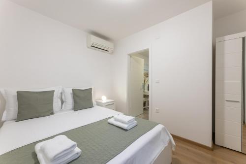 - une chambre blanche avec un grand lit et des serviettes dans l'établissement Apartment ALEX in Kaštel Novi, à Kaštela