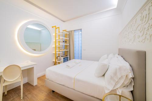 a white bedroom with a bed and a round window at CiuriTaormina Maison de Charme in Taormina