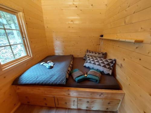 uma cama num chalé de madeira com uma janela em Tiny House am Teich em Garnsdorf