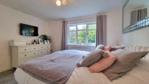 a bedroom with a bed with pillows and a window at Bluebell House Home in country village. NEC/Stratford/Birmingham in Solihull