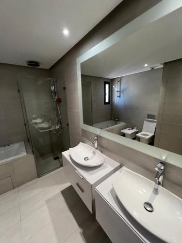 La salle de bains est pourvue de 2 lavabos, d'une douche et d'un miroir. dans l'établissement Appartement Ocean View - Marina Casablanca, à Casablanca