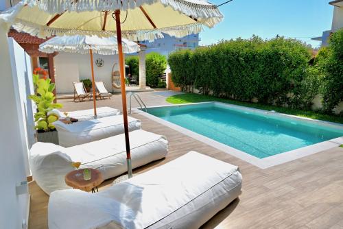 una piscina con due sedie a sdraio e un ombrellone di Mediterranean Luxury Villa a Ialyssos
