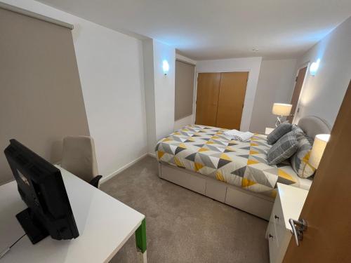 een slaapkamer met een bed en een bureau met een televisie bij Ensuite Room in Royal Victoria Excel O2 Arena London in Londen