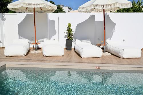 - une piscine avec des chaises et des parasols blancs à côté de la piscine dans l'établissement Mediterranean Luxury Villa, à Ialyssos