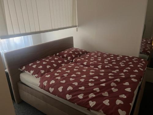 uma cama com uma colcha vermelha com corações brancos em Rekreační byt 3+1 em Železná Ruda