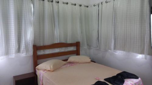 a small bedroom with a bed with white curtains at Pousadinha Ateliê da Maite in Paraty