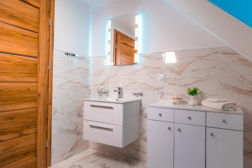 a white bathroom with a sink and a mirror at Dusznickie Apartamenty Julia in Duszniki Zdrój