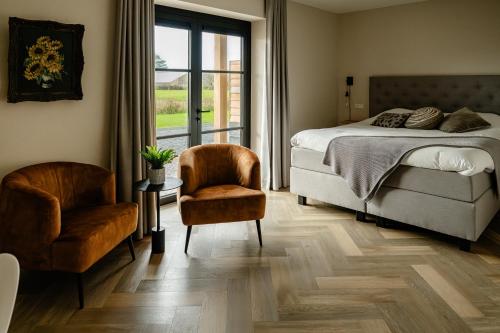 a bedroom with a bed and a chair and a window at B&B de Cley in Noordwijk