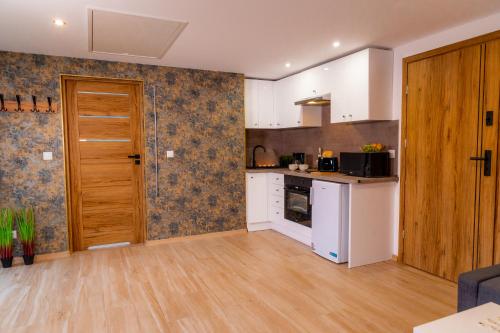 a kitchen with white cabinets and a wooden door at Dusznickie Apartamenty Julia in Duszniki Zdrój