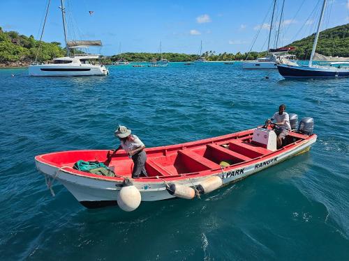 Wild Lotus Glamping - Mayreau, Tobago Cays في Mayreau Island: رجلان في قارب احمر في الماء