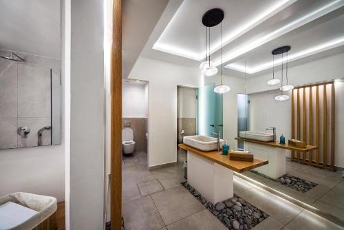 een badkamer met 2 wastafels, een douche en een toilet bij Malia Mare Hotel in Malia