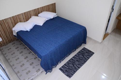 a bedroom with a blue bed with a blue blanket and a rug at Villa Encantos Casa de Campo in Serra Negra