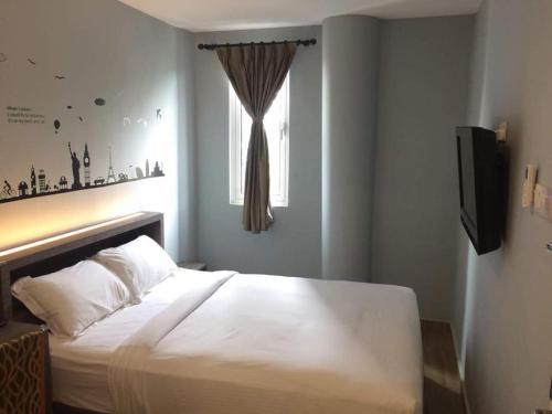 um quarto com uma cama branca e uma janela em Sunlight Hotel Kulai em Kulai
