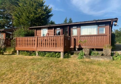 a tiny house with a deck on a lawn at Snug and cosy log cabin. in Trawsfynydd