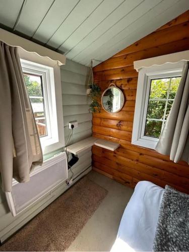 a bedroom with two windows in a log cabin at Snug and cosy log cabin. in Trawsfynydd
