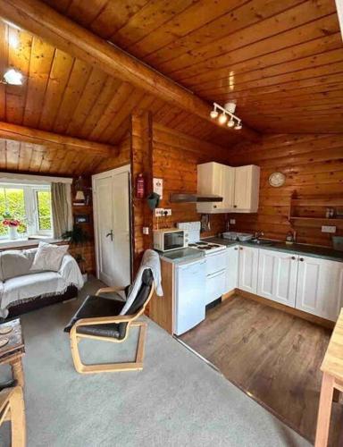 a kitchen in a log cabin with a couch at Snug and cosy log cabin. in Trawsfynydd
