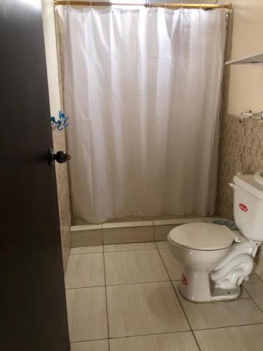 a bathroom with a white shower curtain and a toilet at Hospedaje Maluli Suit 5 in Santa Elena