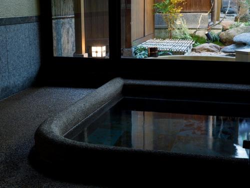 una piscina de agua frente a una ventana en 井波古香里庵 別邸 瑞雲 en Nanto