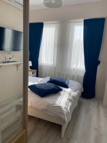 a bedroom with a bed with blue curtains and a mirror at HOUSE KA HANIM in Çanakkale