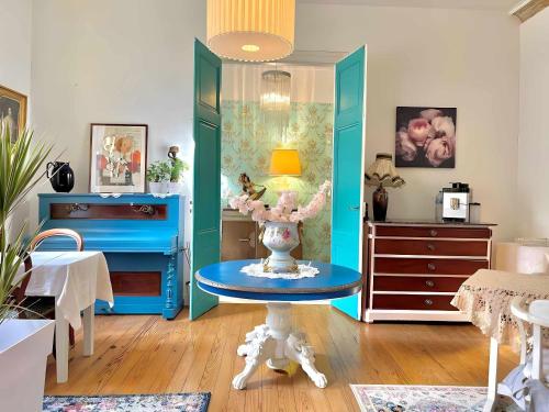 貝爾熱拉克的住宿－Maison B，一间设有蓝色家具和一张带花瓶的桌子的房间