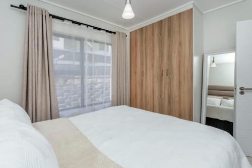 een slaapkamer met een wit bed en een raam bij @The Genesis near OR Tambo Airport in Boksburg
