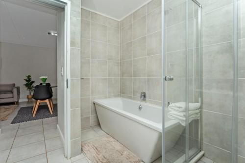 a bathroom with a tub and a glass shower at @The Genesis near OR Tambo Airport in Boksburg