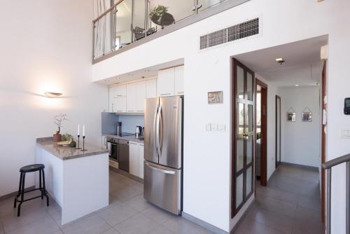 a kitchen with white cabinets and a stainless steel refrigerator at Neve Tsedek 2BR Apartment By Nimizz in Tel Aviv