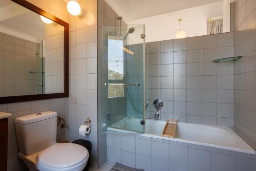 y baño con bañera, aseo y ducha. en Neve Tsedek 2BR Apartment By Nimizz, en Tel Aviv