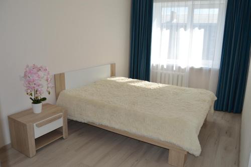 a bedroom with a bed and a table and a window at P Apartment in Rēzekne