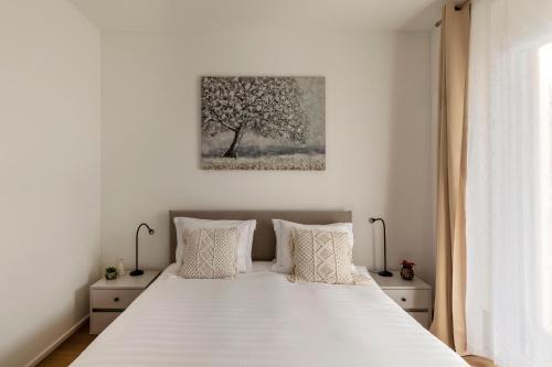 a bedroom with a white bed with a tree picture on the wall at Lugano Superior Suites - Free Parking in Lugano