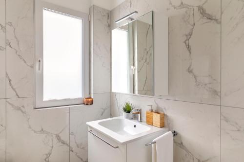 a white bathroom with a sink and a mirror at Lugano Superior Suites - Free Parking in Lugano