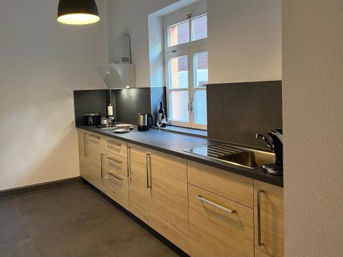 cocina con armarios de madera, fregadero y ventana en Old Town Apartment en Rottweil