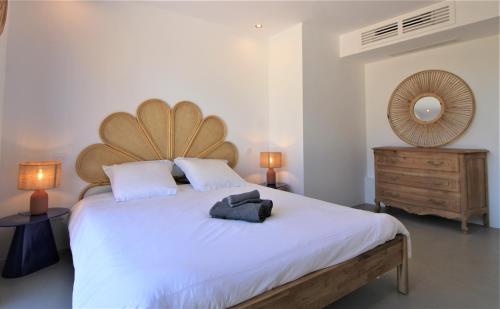 a bedroom with a large white bed with a wooden headboard at La madrague-Villa/Piscine vue Mer/Clim/Wifi in Hyères