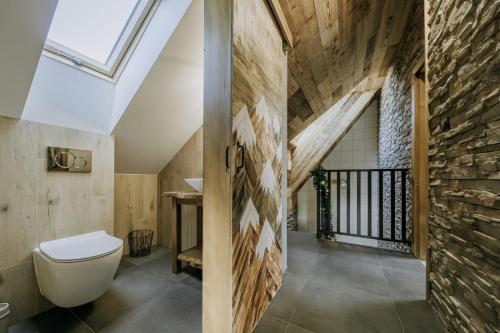 a bathroom with a toilet and a stone wall at Luxury Chalet Kajmer in Jurgów