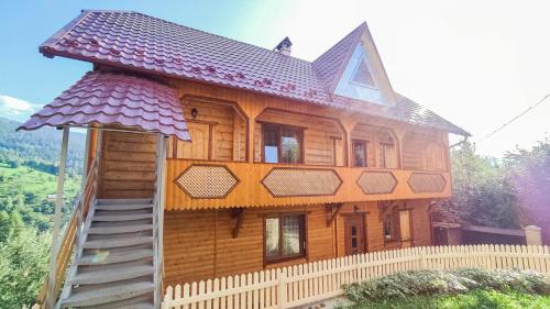 uma grande casa de madeira com uma cerca em frente em Котедж Біля лісу em Yaremche