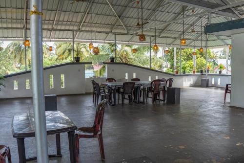 a dining room with tables and chairs and windows at White House Residency in Varkala