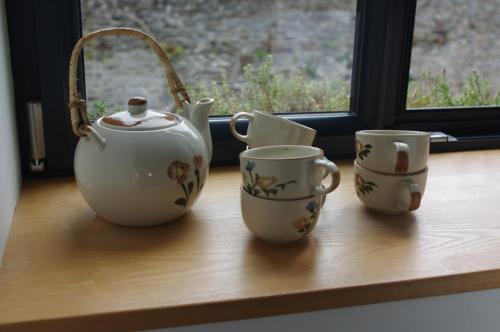 trois tasses de thé et une théière sur un rebord de fenêtre dans l'établissement Cosy ferme de village en baie du Mont Saint Michel, à Vains