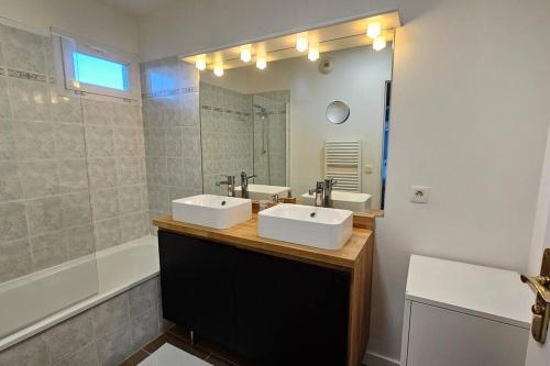 ein Badezimmer mit zwei Waschbecken, einem Spiegel und einer Badewanne in der Unterkunft Le Clos Fleury in Thonon-les-Bains