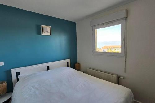 ein blaues Schlafzimmer mit einem Bett und einem Fenster in der Unterkunft Le Clos Fleury in Thonon-les-Bains