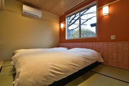 a bedroom with a white bed and a window at Ryokan Sakaya in Nozawa Onsen