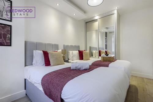twee bedden in een slaapkamer met een spiegel bij 1 Bed 1 Bath Town Center Apartments For Corporates & Contractors, FREE Parking, WiFi & Netflix By REDWOOD STAYS in Aldershot
