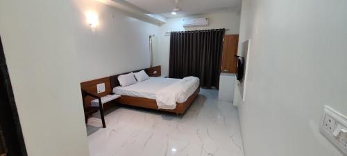 Dormitorio pequeño con cama y TV en Hotel Mayur Residency, en Ellora