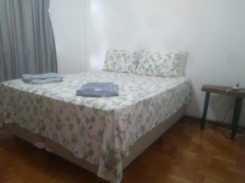 een slaapkamer met een bed met een deken en kussens bij Apartamento Jardim Cascata in Teresópolis