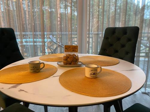 a table with two cups and a plate of food at Apartamentai Ornamentai in Druskininkai