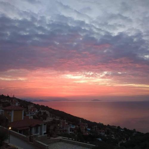 a sunset over the ocean with houses and a city at Apollo Romantic Sea View Villa in Kivérion