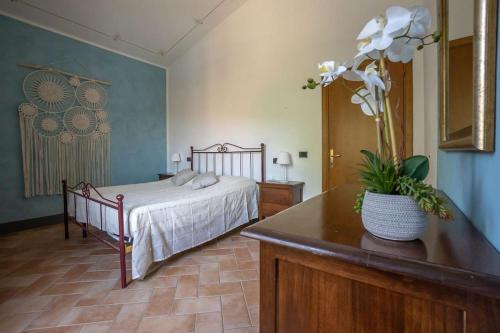 Un dormitorio con una cama y una mesa con un jarrón de flores en Terra di Mezzo en Volterra