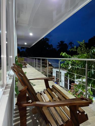 une chaise en bois assise sur un balcon la nuit dans l'établissement Hotel Serendipity, à Tortuguero